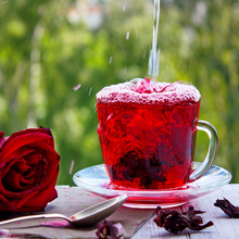 Load image into Gallery viewer, Outdoor glass of carcade drink from red calyx flower infusion of perennial garden plant Florida Cranberry Hibiscus sabdariffa